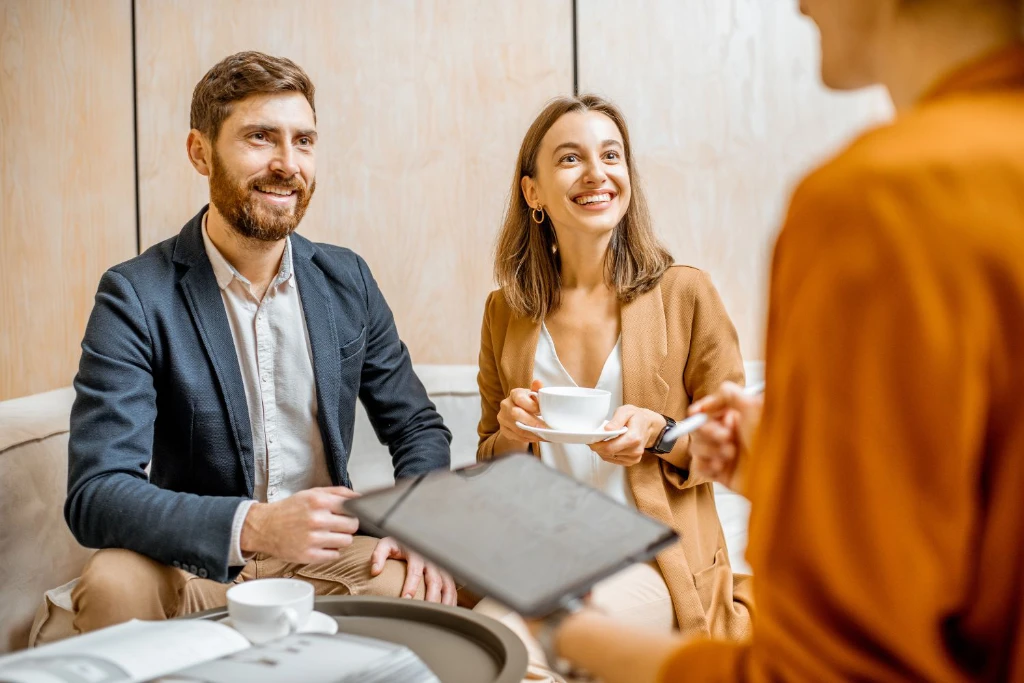 Smiling couple chatting with a property management agent over coffee
