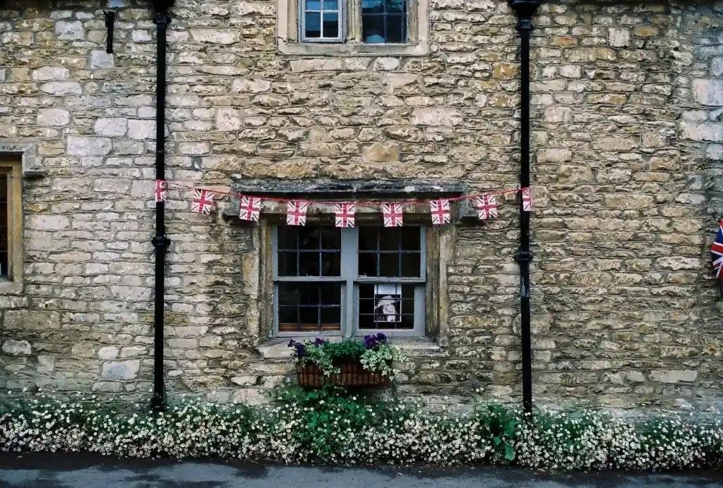 A traditional stone cottage window dressed with bunting and flowers