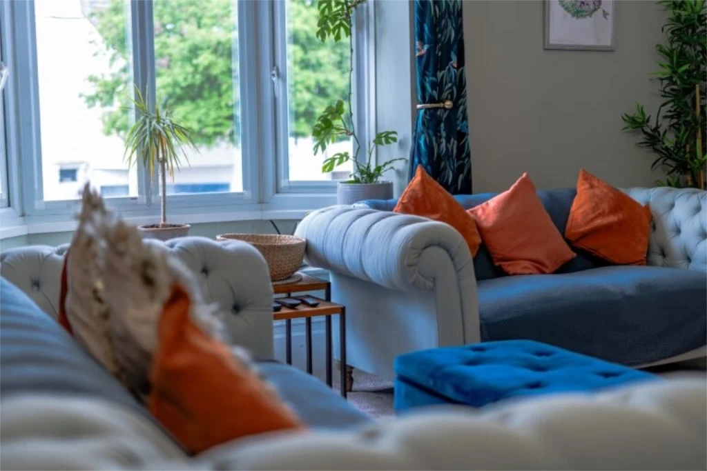Property management lounge renovation featuring white Chesterfield sofa with orange accent pillows and modern styling
