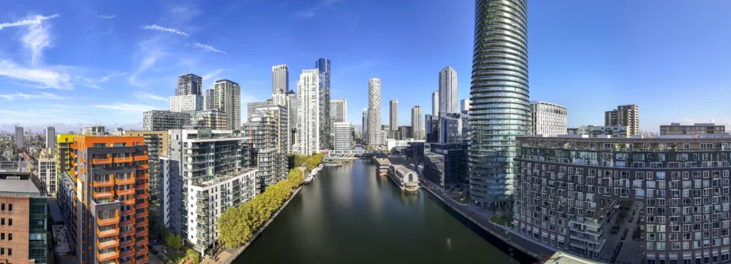 Panoramic view of East London Docklands canal with modern residential towers and mixed-use developments