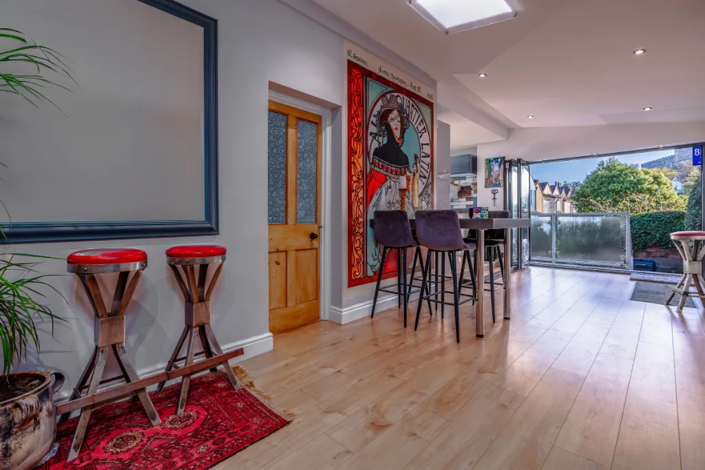 Room with bar stools, artwork, and wooden flooring