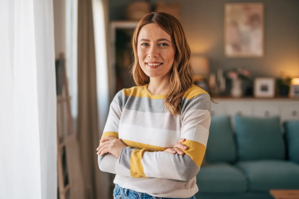 Smiling woman posing with arms crossed in a bright indoor space