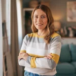 Smiling woman posing with arms crossed in a bright indoor space